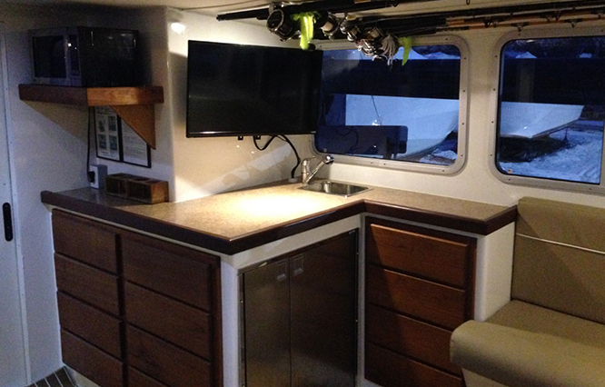 Internal view of the boat (galley) showing a counter, TV, fridge, microwave and drawers