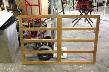 Wooden frames standing upright sit in the work garage ready to be installed.