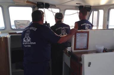 View from within the deckhouse looking towards the captain's chair looking at the back of Captain Steve and 3 guys from Atlantic Service & Equipment with their branded t-shirts on