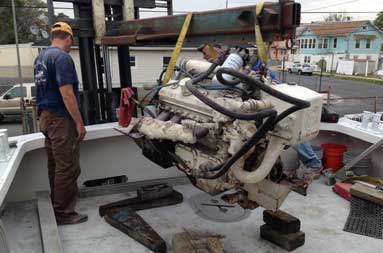 Capt. Steve watches as heavy machinery is used to lift the engine off the boat