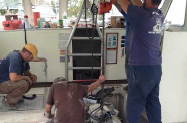 Capt. Steve and two men from T&S Marine use equipment to prepare the lift of the engine