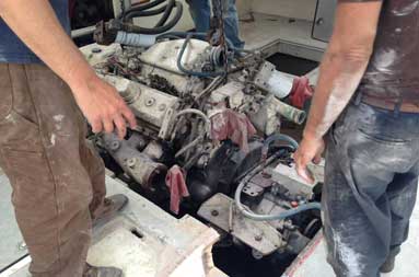 Capt. Steve and two men from T&S Marine watch as the engine is slowly lifted up