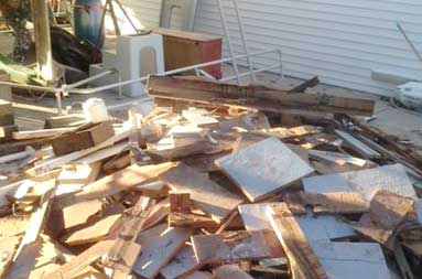 A large pile of various sized pieces of cut wood, sitting where the new deck will be