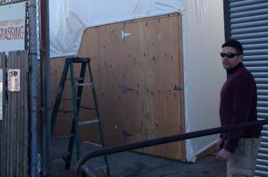 Captain Steve standing near the wooden makeshift backdoor entrance of the giant tent that will house the boat while it's being worked on during the cold winter months