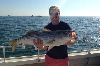 The same guy from the previous photo smiling holding up his bass