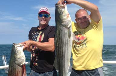 Two of the guys each holding up the large bass they caught