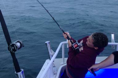 The other young boy, Daniel, reeling in a fish
