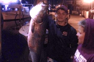 A night shot of Jacob standing next to his fish being weighed