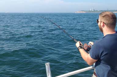 Another one of the guys reeling in a fish from the side of the boat