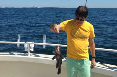 One of the kids looking at a porgy that he caught hanging on the line