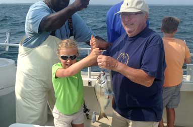 First mate Gil helping one of the young girls hold up a porgy/scup she caught