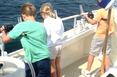 The three kids looking over the railing as they fish