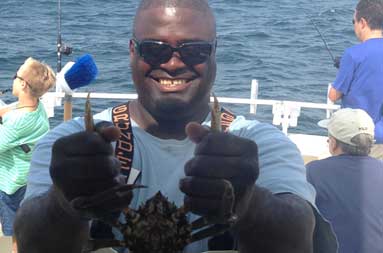 First mate, Gil, smiling as he holds up a crab