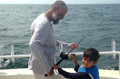 One of the adults working with one of the kids to use the rod