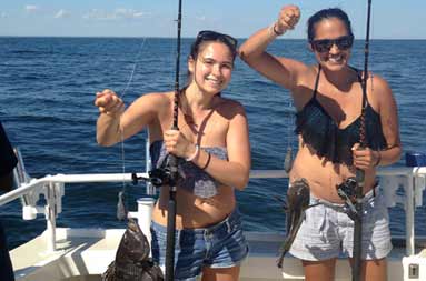Two of the women holding up their catch still on the reel