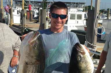 One of the guys back at the marina holding up two striped bass that he caught