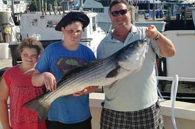 Three of the guests holding up a large bass