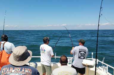 View of the back of the guys reeling in a fish from the boat