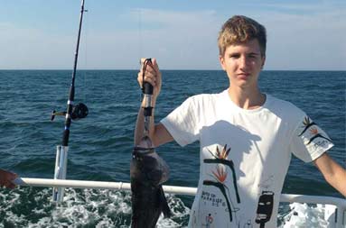 One of the adolescent boys holding up his catch