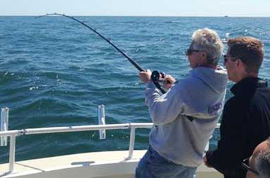 One of the guys, Alan, standing on the boat reeling in his catch.