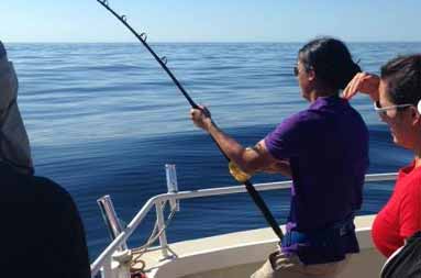 One of the guests standing on the boat reeling in their catch