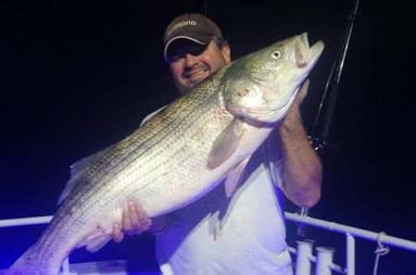 Night shot of one of the guys holding up a large bass.