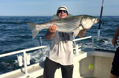  Another one of the guys on the boat holding up the striped bass he caught.