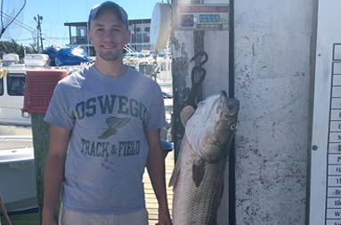 A man standing next to his catch hanging on the scale back at the marina.