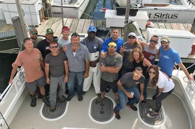 Photo taken from the top of the boat looking down at a group of men and women smiling.