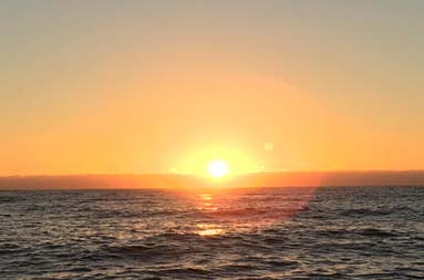 View from the boat looking out over the ocean, as slowly ascends at the beginning of sunrise.