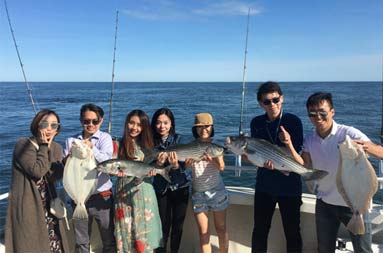 A group shot of everyone aboard the boat holding their catch.