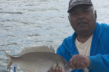 A man aboard the boat holds the porgy (scup)he caught.