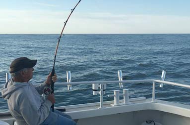 One of the men, Matt, 75 years old, sits back in the chair and holds onto his reel waiting for a bite.