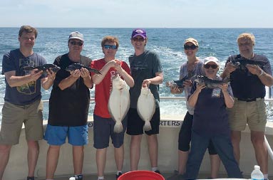 A family of 7 each hold up the fish they caught.