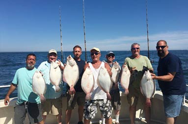 A group of 7 men each hold up the fluke they caught.