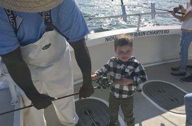 First mate, Gil, holds up the end of the reel as the young boy grabs hold of the handle.