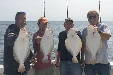 Four men each hold up one fluke.