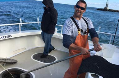 The first mate smiles for the camera as he assists with fixing the boat's steering.