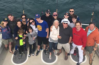 View looking down at the deck of a family of 17 people smiling up at the camera