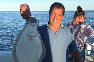 A man proudly holds up his fluke.