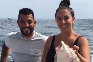 A man and woman smile for the camera while the woman holds up fluke.
