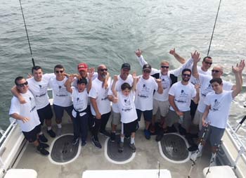 View from atop the boat looking down at the deck of 14 men and boys enthusiastically smiling for the camera.