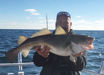 Close up of a man holding up a sea bass.