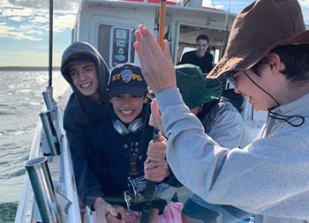 A group of friends help another friend reel in her catch.