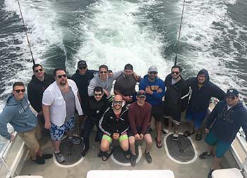 View from atop the boat looking down at a group of 13 men smiling for the camera.