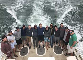 View from atop the boat looking down at a group of 13 men smiling for the camera.