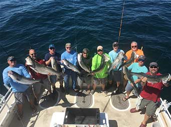 View from attop the boat looking down at a group of 10 men each holding up striped bass.