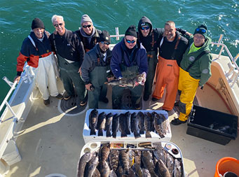 Overhead shot from top of the boat of 8 men standing around the fillet table with fish on it