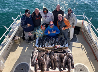 Overhead shot from top of the boat of a group of men standing around the fillet table with fish on it